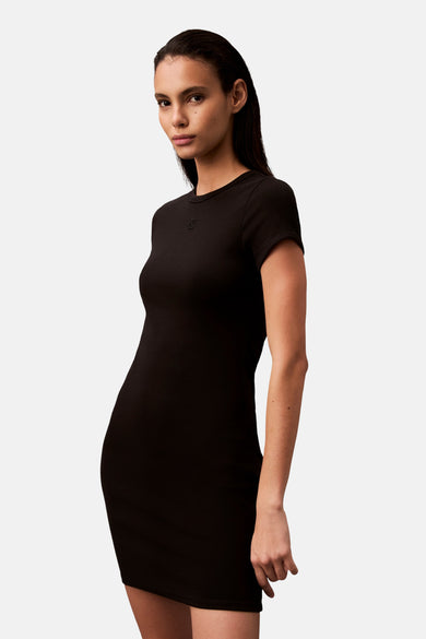 Robe courte noire de Calvin Klein, moulante et à manches courtes sur fond neutre.
