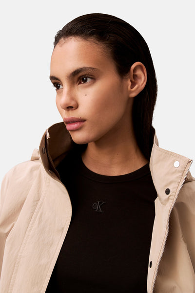 Robe courte noire de Calvin Klein, portée avec une veste beige à col montant, vue de trois quarts.