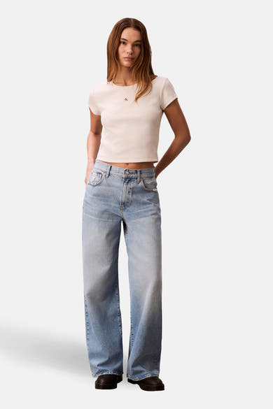 Ecru T-shirt met korte mouwen van Calvin Klein, gedragen met een high-waisted jeans en zwarte schoenen.