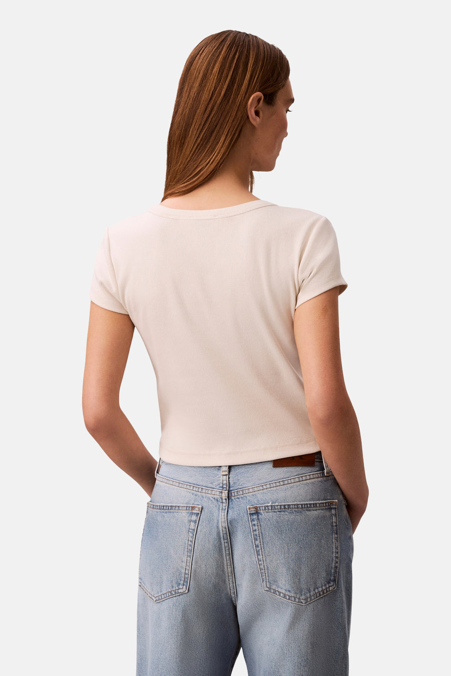 Ecru T-shirt met korte mouwen van Calvin Klein, in ribgebreide stof, gedragen met een high-waisted jeans.