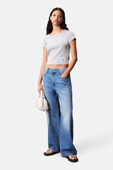 T-shirt gris à manches courtes de Calvin Klein, porté avec un jean bleu taille haute et un sac blanc.

