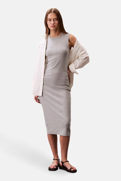Robe grise de Calvin Klein avec chemise ouverte crème et sandales noires.