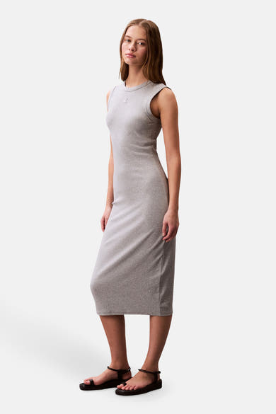 Robe grise à manches courtes de Calvin Klein, longueur midi moulante et paire de sandales noires.