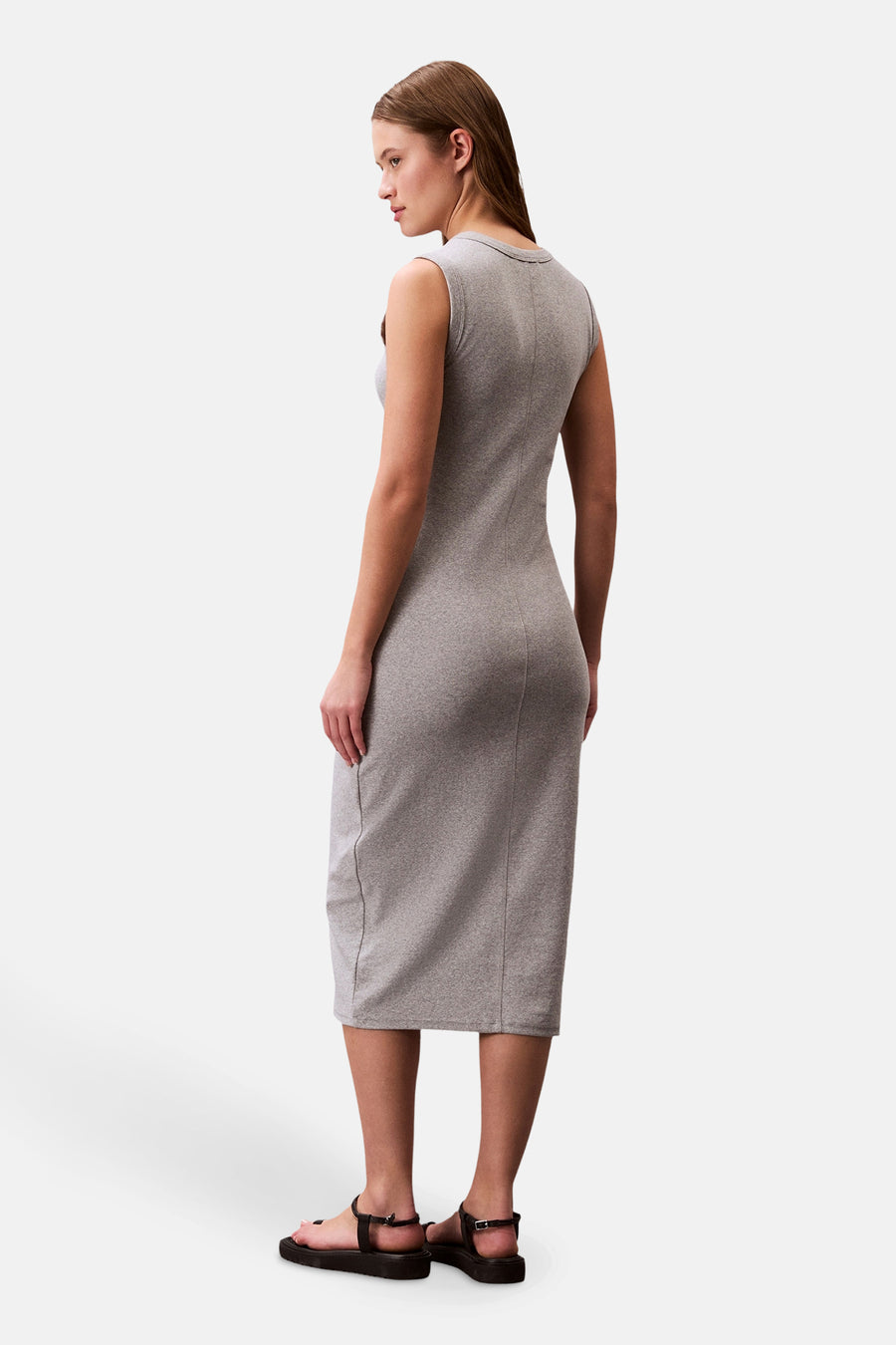 Robe moulante grise de Calvin Klein, mi-longue et sans manches, portée avec des sandales noires à plateforme.