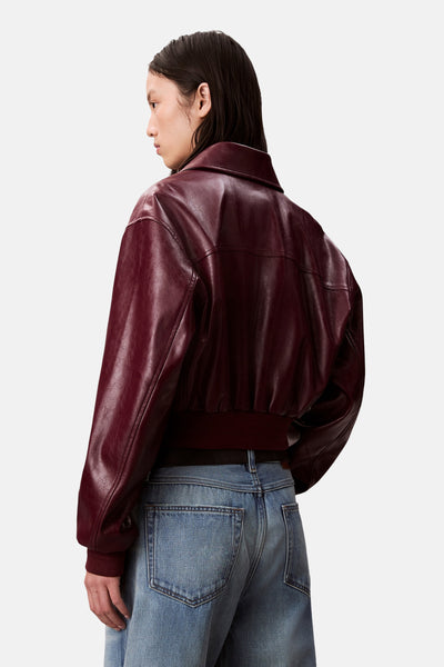 Veste courte bordeaux de Calvin Klein, avec un col classique et portée avec un jean bleu décontracté.
