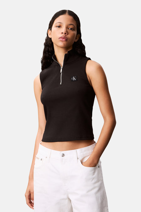 Zwart mouwloos topje van Calvin Klein met ritssluiting, gedragen met een witte broek.
