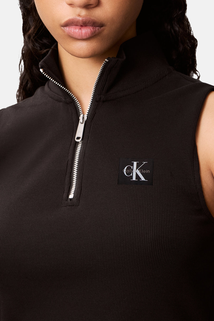 Top noir sans manches de Calvin Klein avec fermeture éclair argentée et logo de la marque.