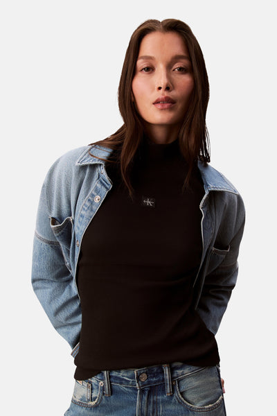 Zwart T-shirt met lange mouwen van Calvin Klein, gedragen met een spijkeroverhemd en een spijkerbroek.