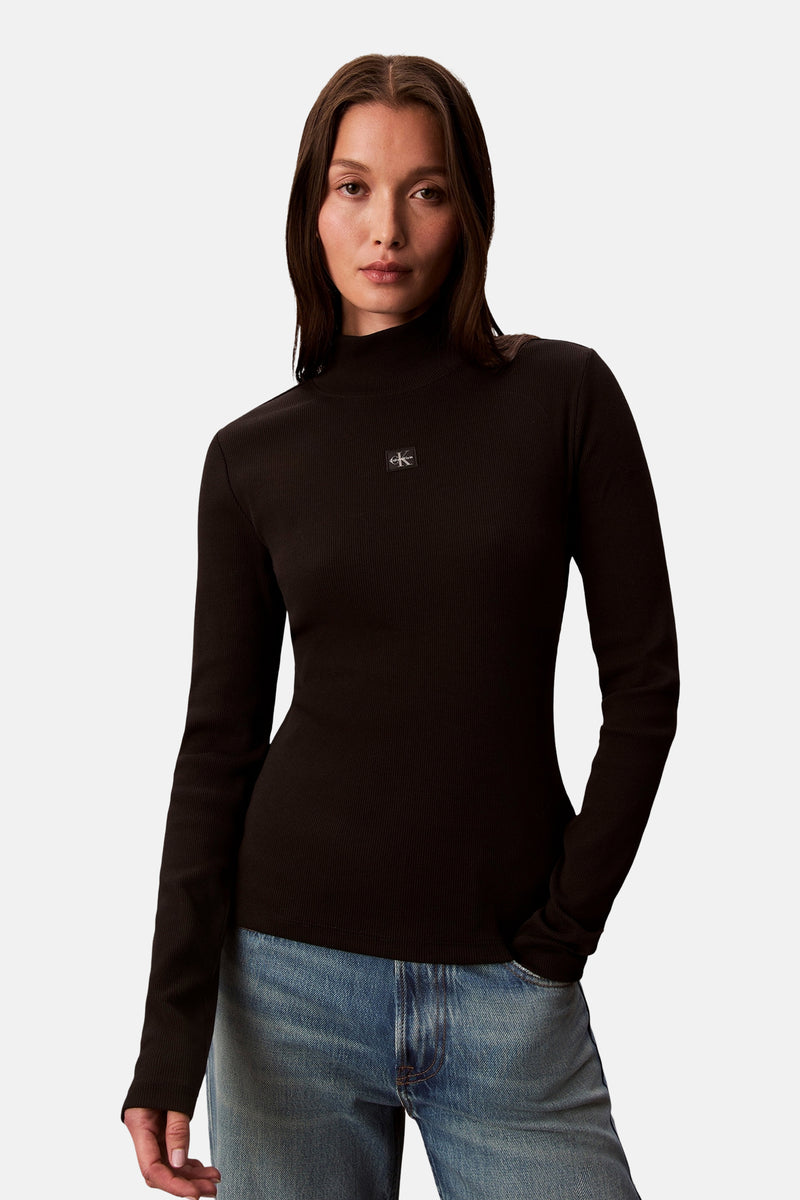 Zwart T-shirt met lange mouwen van Calvin Klein, in geribde stof, gedragen met een spijkerbroek.