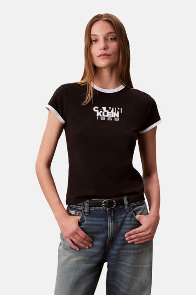 Effaatzwart T-shirt met korte mouwen van Calvin Klein, met contrasterende witte zoom en gedragen met een high-waisted jeans.