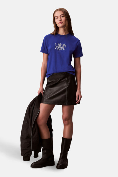 Blauw T-shirt met korte mouwen van Calvin Klein, gedragen met een zwarte leren rok en bijpassende laarzen.