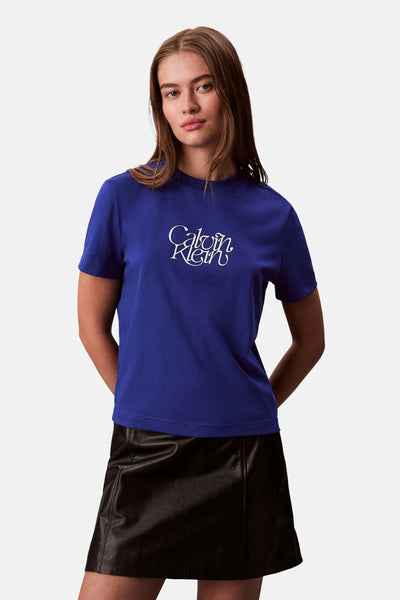 Blauw T-shirt met korte mouwen van Calvin Klein met decoratief wit logo, gedragen met een zwarte leren minirok.