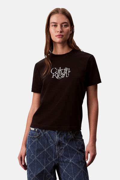 Zwart T-shirt met korte mouwen van Calvin Klein, gedragen met een blauwe spijkerbroek met ruitpatroon.
