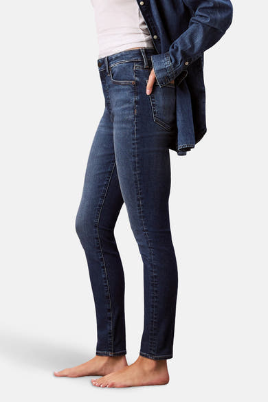Jean skinny bleu moyen en denim par Calvin Klein, porté avec une chemise en jean et un débardeur blanc.