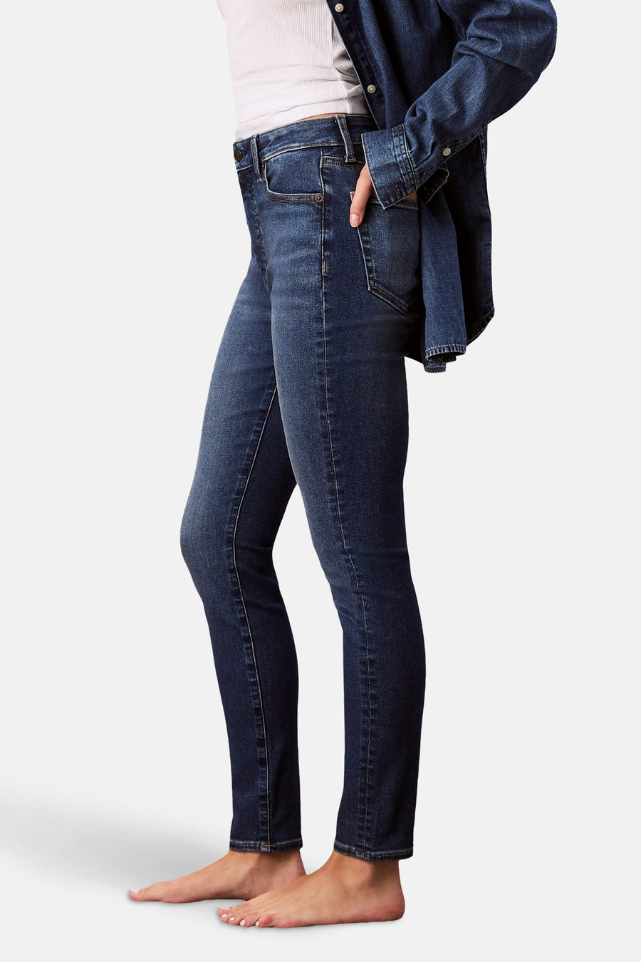 Jean skinny bleu moyen en denim par Calvin Klein, porté avec une chemise en jean et un débardeur blanc.