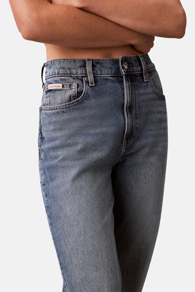 Jean Mom bleu moyen de Calvin Klein, avec une coupe taille haute et des détails délavés.
