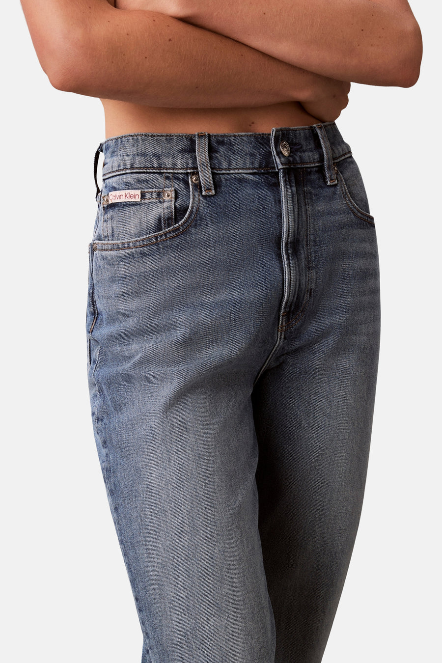 Jean Mom bleu moyen de Calvin Klein, avec une coupe taille haute et des détails délavés.
