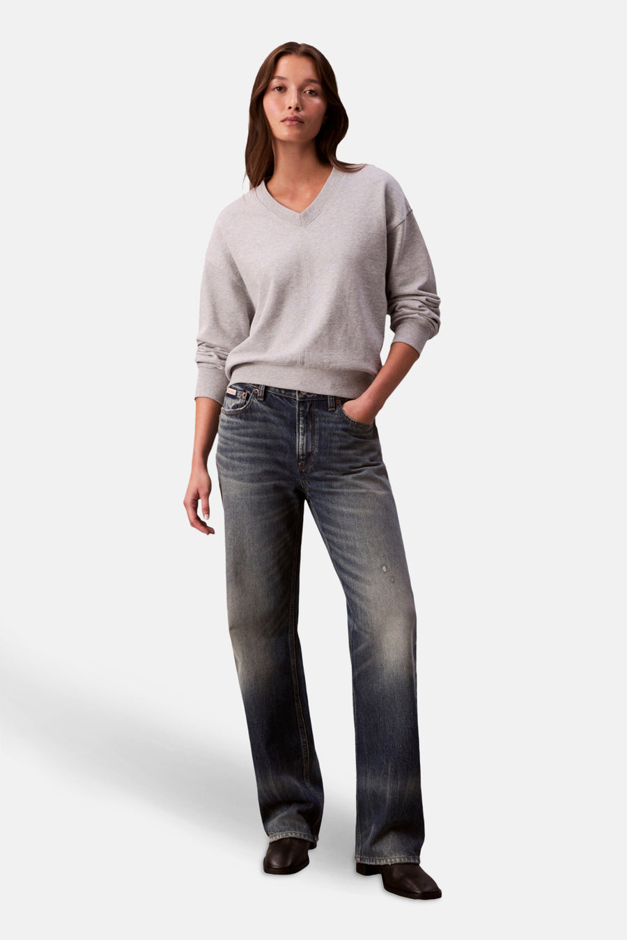 Sweat gris de Calvin Klein, porté avec un jean délavé et des chaussures noires.