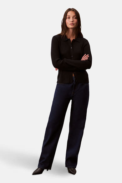 Zwarte cardigan met klassieke kraag van Calvin Klein, gedragen met een donkerblauwe jeans en zwarte pumps.