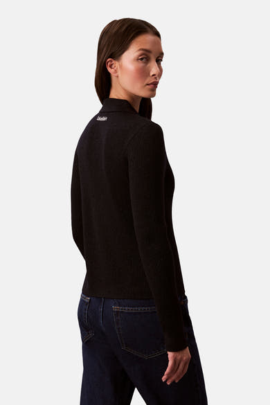 Marineblauwe geribbelde cardigan van Calvin Klein, met logo op de halslijn, gedragen met een donkere spijkerbroek.