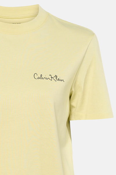 T-shirt jaune à manches courtes de Calvin Klein, avec logo manuscrit noir sur la poitrine.