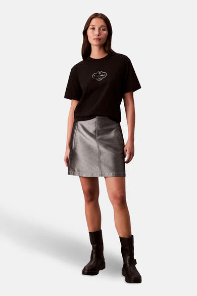 Zwart T-shirt met korte mouwen van Calvin Klein, gedragen met een zilveren rok en laarzen.