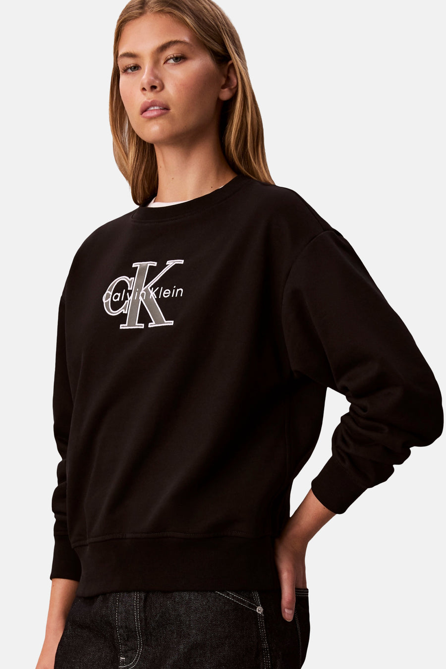 Zwart Calvin Klein sweatshirt met ronde hals, met logo op de voorkant, gedragen met een donkere spijkerbroek.