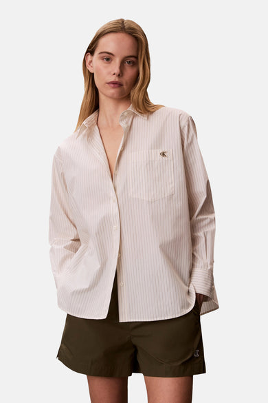Beige gestreept overhemd met lange mouwen van Calvin Klein, met borstzak en logo, gedragen met een olijfgroene korte broek.
