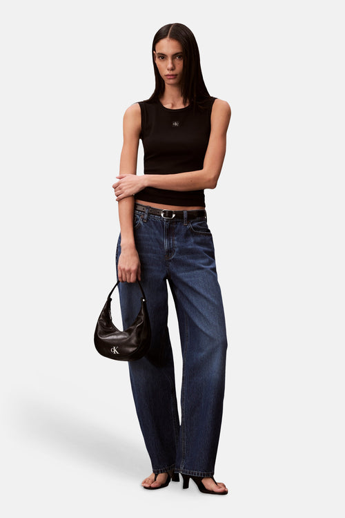 Débardeur noir de Calvin Klein, porté avec un jean large et un sac à main noir.
