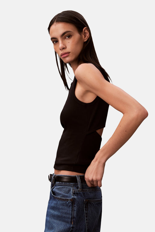 Débardeur noir de Calvin Klein avec une coupe sur le côté, porté avec un jean taille haute.