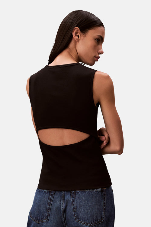 Débardeur noir en maille côtelée de Calvin Klein avec découpe au dos, porté avec un jean taille haute.
