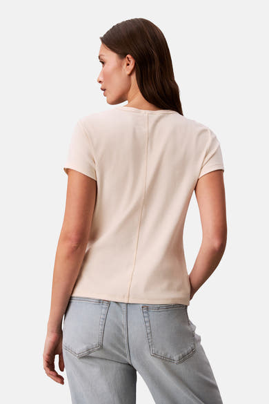 Ecru gilet van Calvin Klein, met verticale naad in het midden van de rug, gedragen met een verbleekte spijkerbroek.