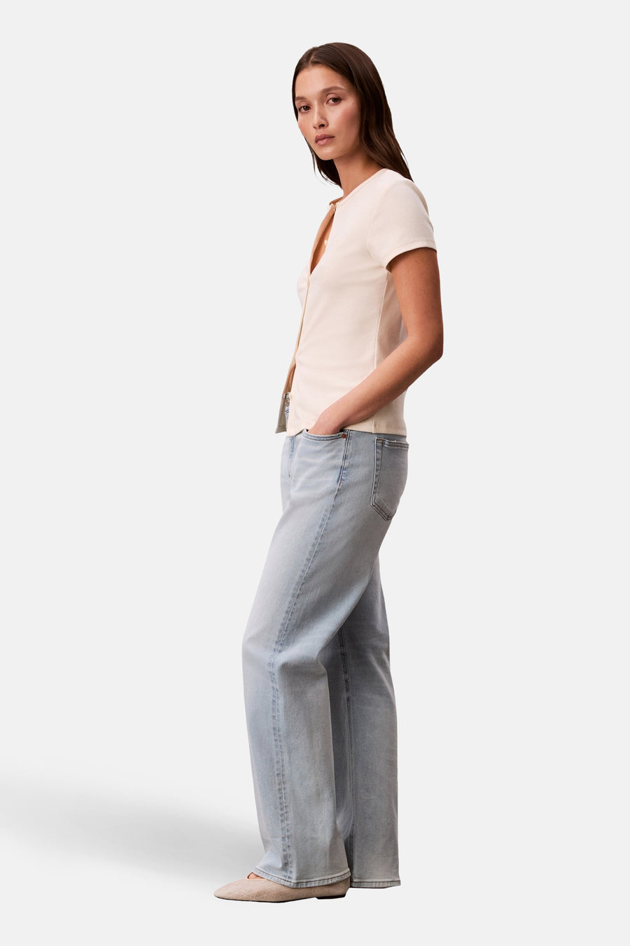 Ecru gilet van Calvin Klein, gedragen met een lichtblauwe wijde pijpen jeans en platte schoenen.