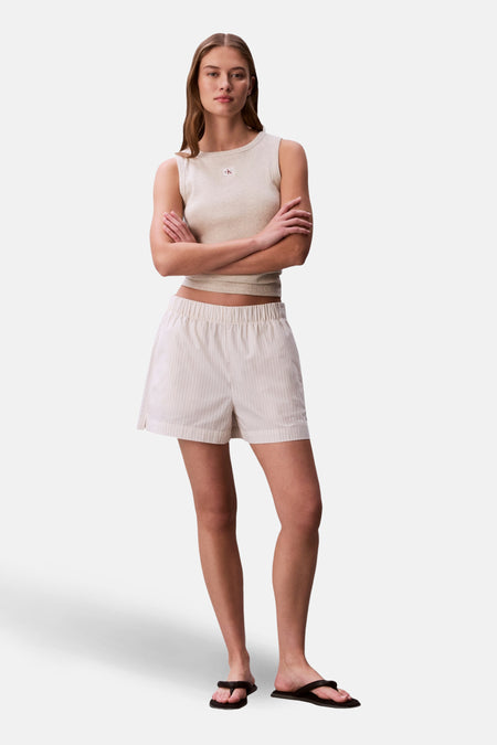 Short rayé blanc cassé et jaune, de Calvin Klein, porté avec un haut neutre et des sandales noires.