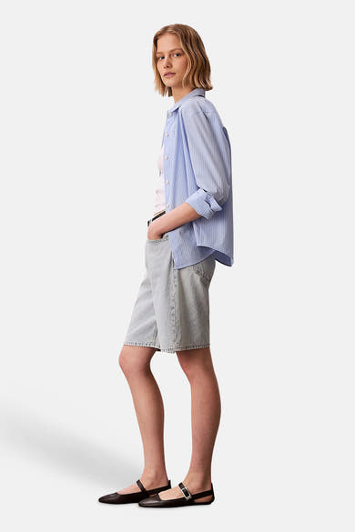 Short en denim bleu clair de Calvin Klein, porté avec une chemise rayée bleue et blanche.