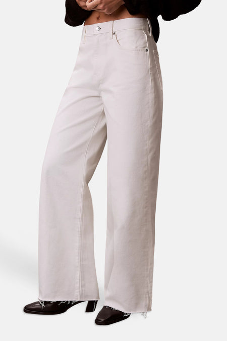 Crèmekleurige wijde spijkerbroek van Calvin Klein, achterkant met bruin reliëf lederen etiket en achterzak.