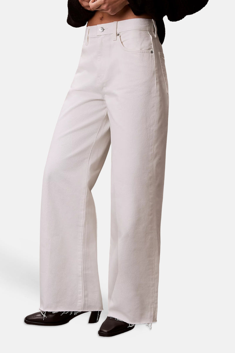 Crèmekleurige wijde spijkerbroek van Calvin Klein, achterkant met bruin reliëf lederen etiket en achterzak.