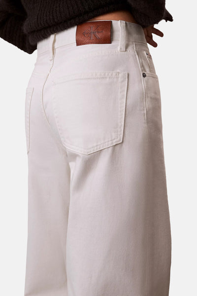 Jean large écru en denim de Calvin Klein, vue arrière avec étiquette en cuir marron gaufrée et poche arrière.