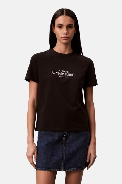 T-shirt noir à manches courtes de Calvin Klein, porté avec une mini-jupe en jean