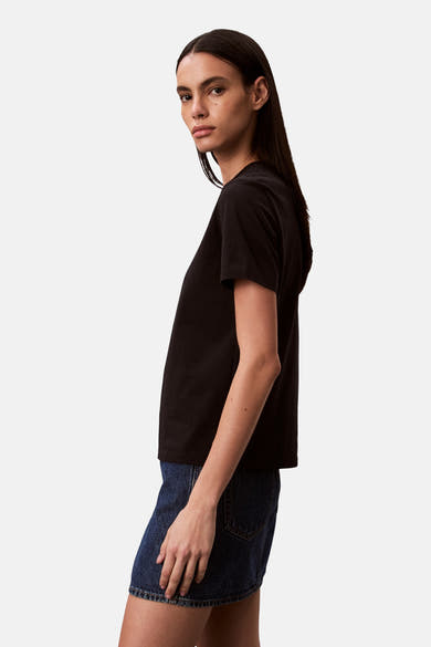 T-shirt noir de Calvin Klein, porté avec une mini-jupe en jean, vu de côté.
