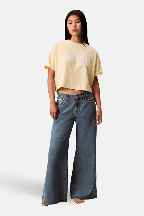 T-shirt court jaune de Calvin Klein, porté avec un jean taille basse ample.
