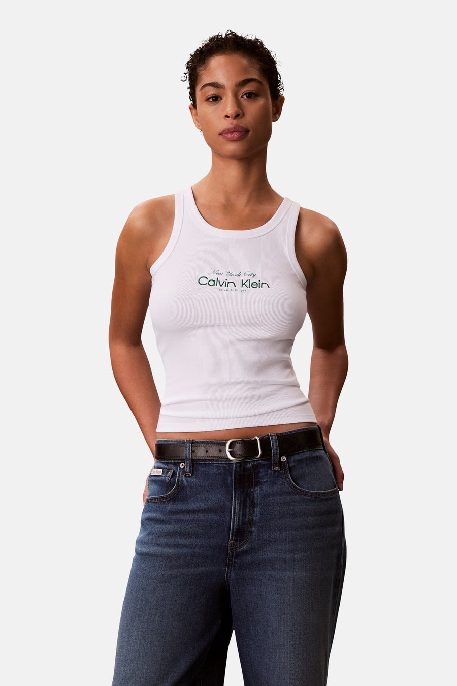 Witte tanktop van Calvin Klein, in geribbelde jersey, gedragen met een high-waisted jeans en een zwarte riem.