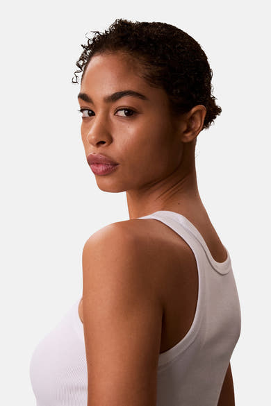 Witte tanktop van Calvin Klein, gedragen door een model dat over haar schouder kijkt.