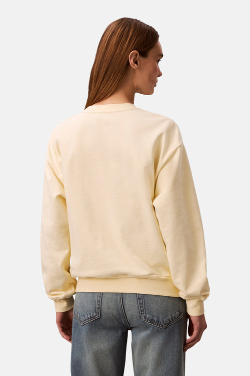 Sweat-shirt jaune de Calvin Klein, uni, avec des manches longues et porté avec un jean.