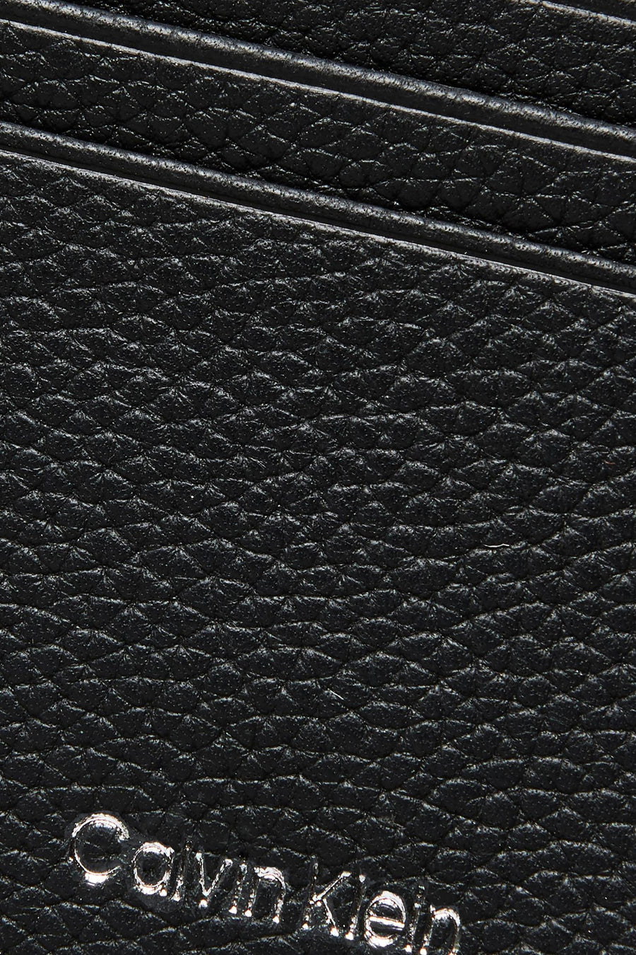 Porte-monnaie en cuir noir de Calvin Klein avec un motif texturé et le logo de la marque.