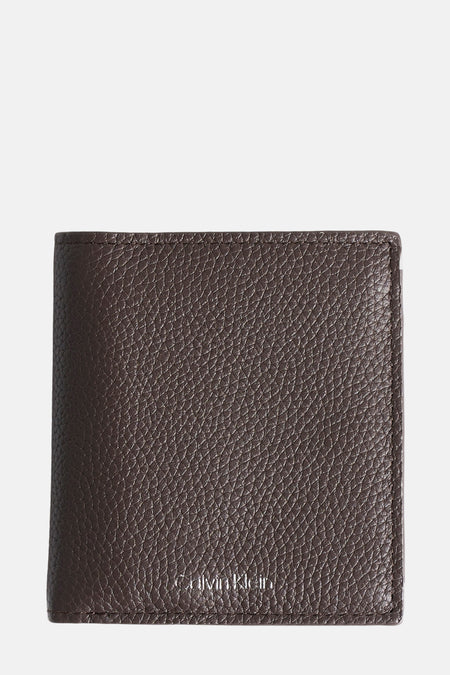 Porte-monnaie en cuir brun de Calvin Klein, avec une texture grainée et le logo discret en bas.
