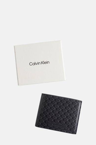 Portefeuille noir de Calvin Klein, avec motif monogramme répété et boîte d'emballage blanche.