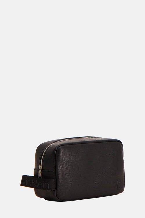 Trousse de toilette noire en cuir de Calvin Klein, avec logo discret et fermeture à glissière apparente.
