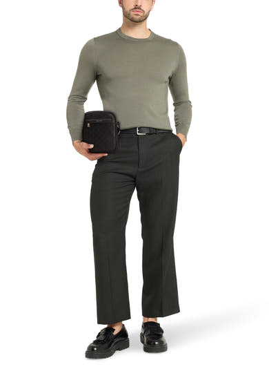Zwarte Calvin Klein schoudertas met subtiel geometrisch patroon, gedragen met een zwarte broek en schoenen.