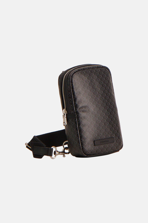 Sac à bandoulière noir de Calvin Klein avec motif de logo répété et bandoulière ajustable.